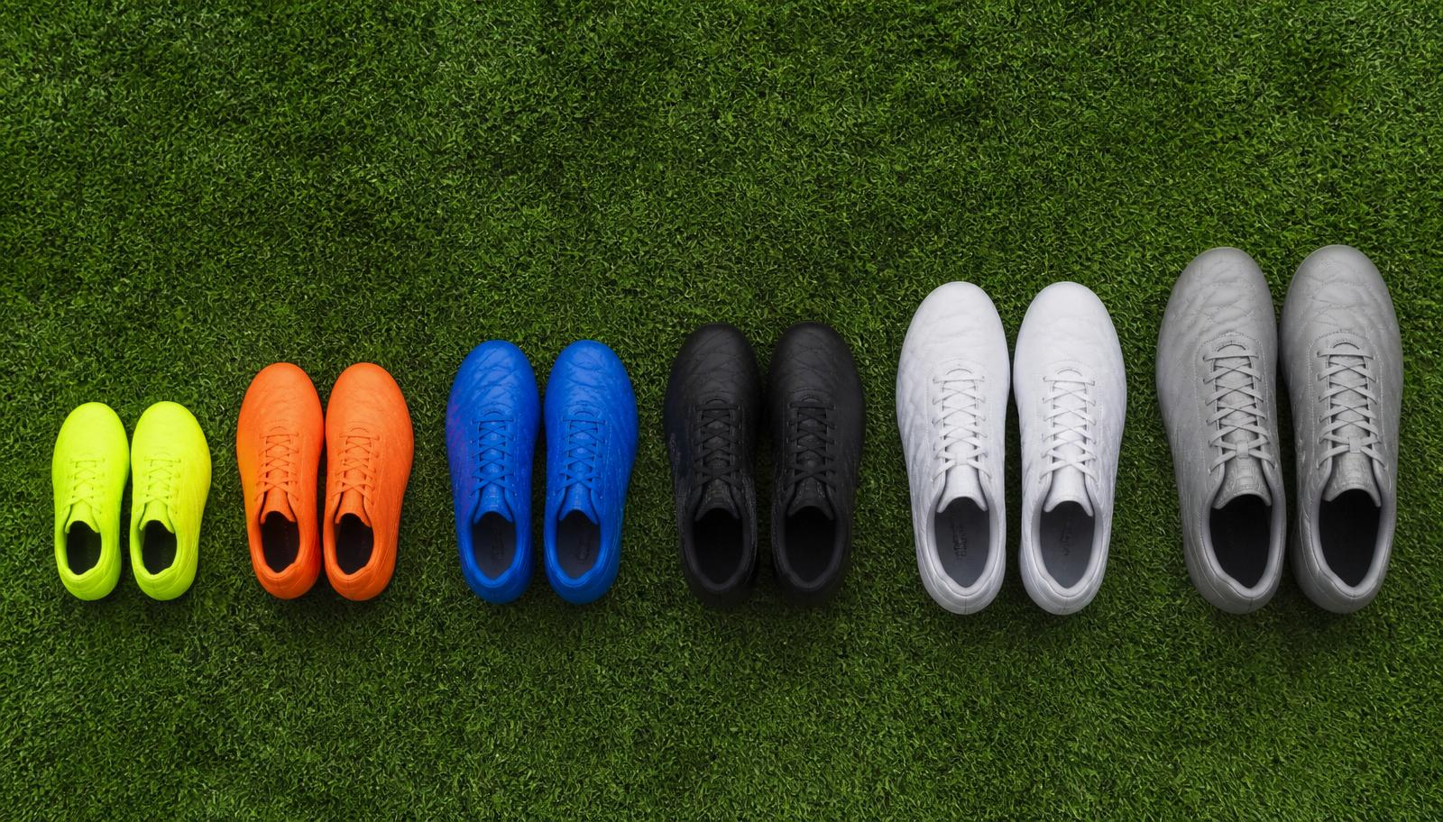 Row of youth soccer cleats in increasing sizes on green turf